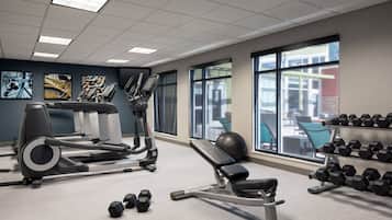 A gym with cardio machines, dumbbells, and exercise balls.