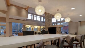 Un amplio comedor interior con una larga mesa y numerosas sillas, una pared de acento de piedra e iluminación colgante.