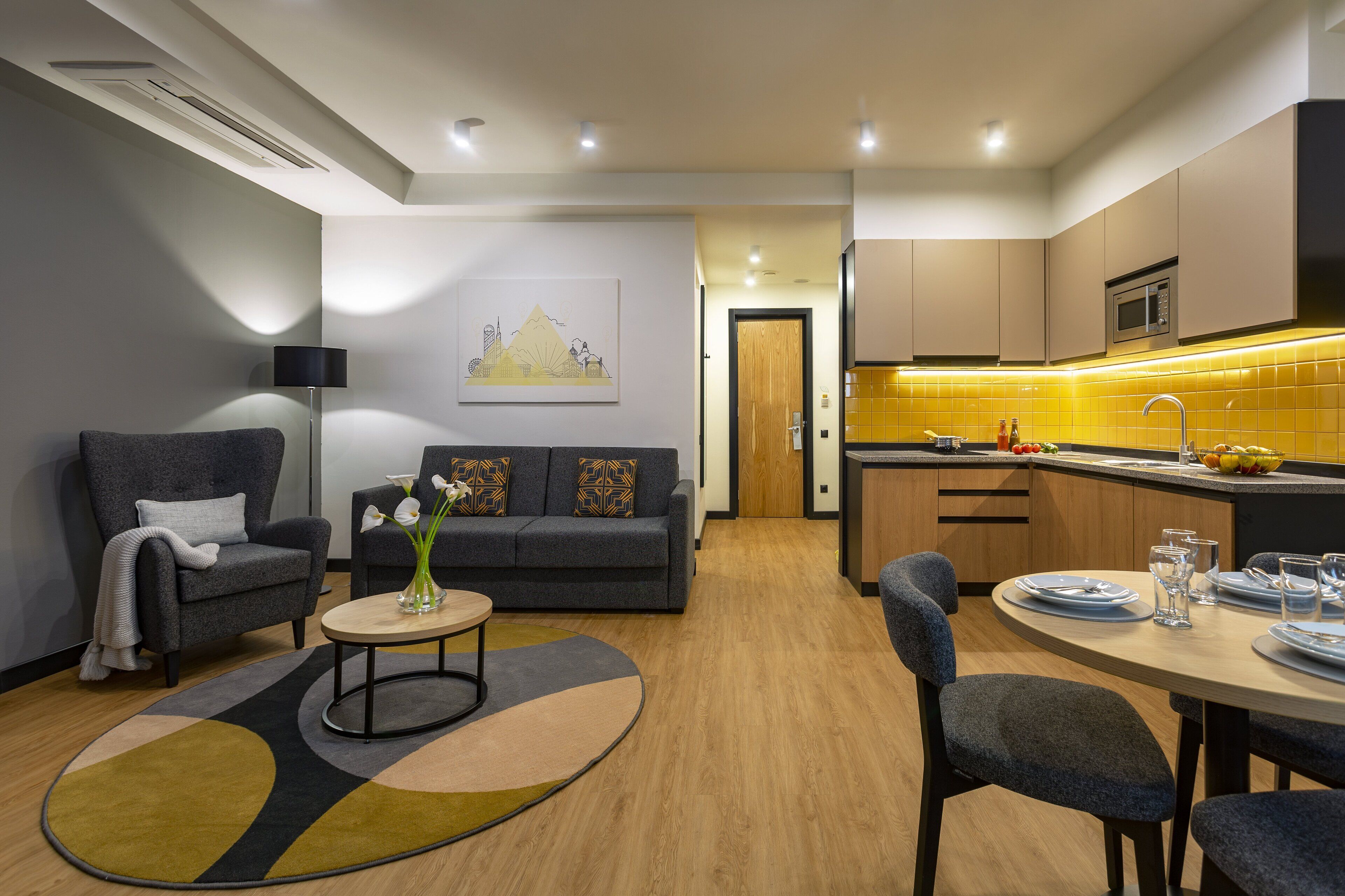 A modern living room with a sofa, armchairs, a coffee table, and a dining area with a table set for two.