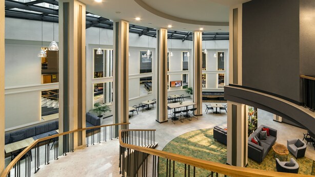 A modern interior with a central staircase, open-plan seating areas, and a mezzanine level. - The Gate Hotel City Centre (Tbilisi)