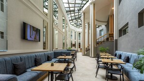 A spacious indoor area with high ceilings, a central staircase, and seating arrangements. - The Gate Hotel City Centre (Tbilisi)