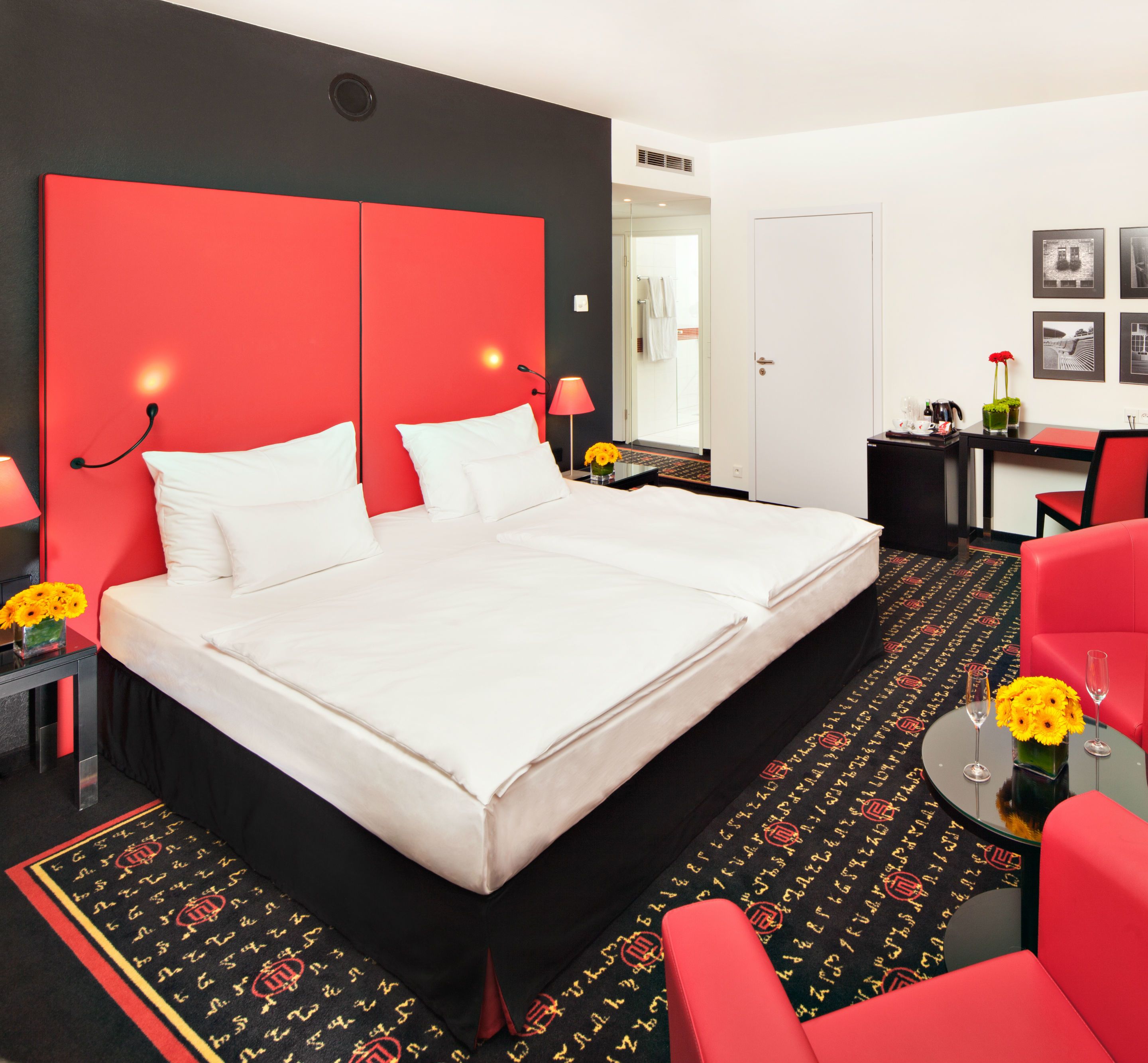 Habitación de hotel con una cama grande, un escritorio, una silla y una mesita con flores.