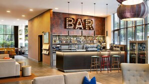 Un espace bar moderne, avec un panneau indiquant « BAR », des sièges et un comptoir bien garni.