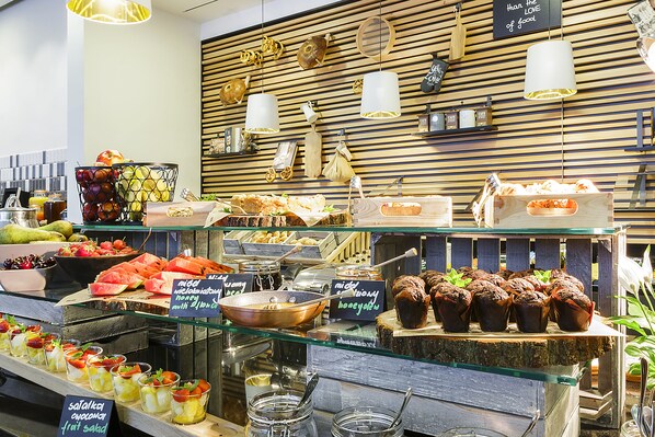 Mostrador de panadería con diversos productos horneados y frutas frescas.