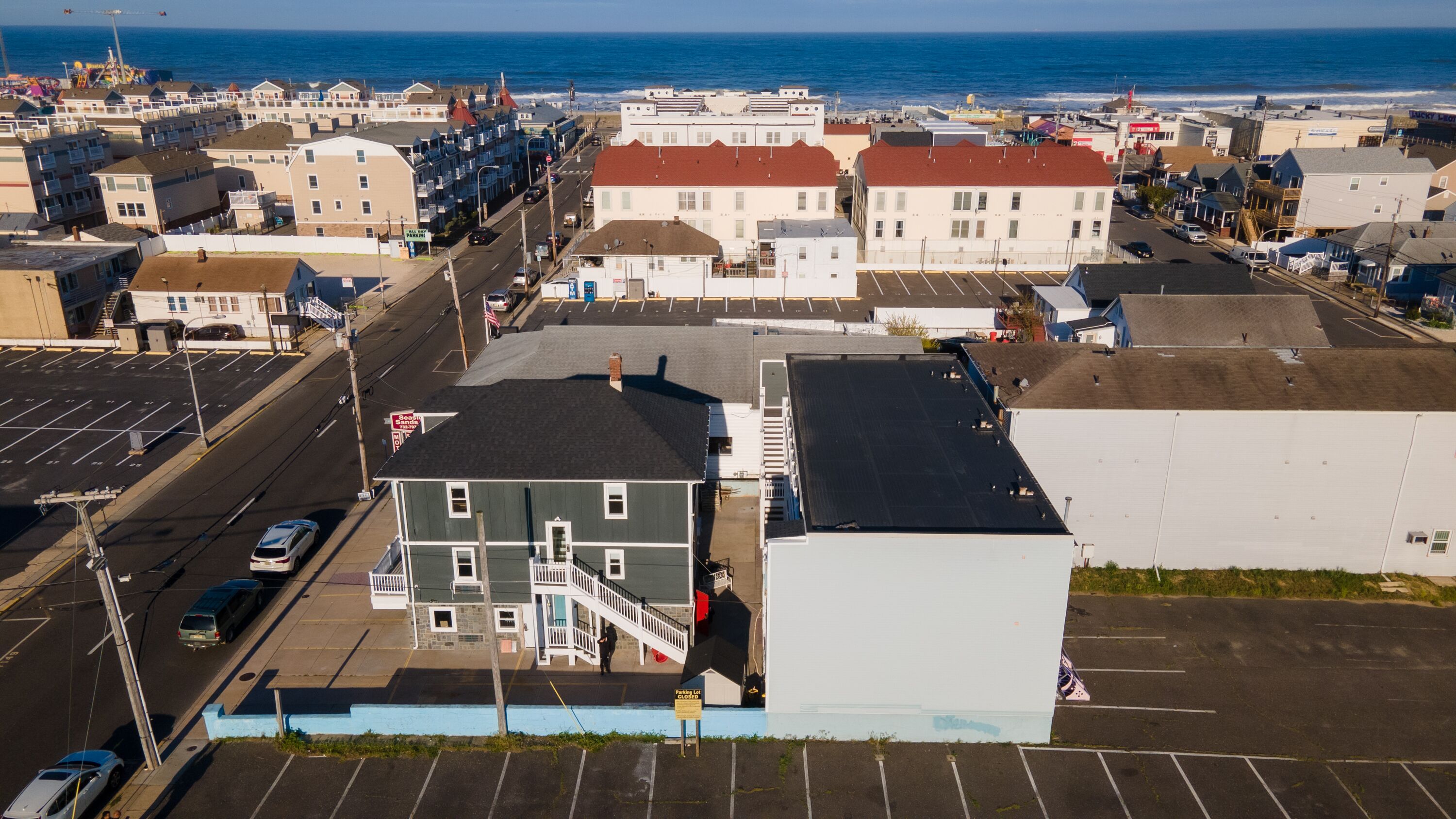 A coastal town with a parking lot, buildings, and a view of the ocean.
