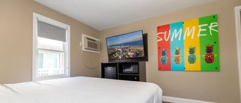 Un dormitorio con cama, televisor, ventana y una pared con un cartel que dice 'SUMMER'.