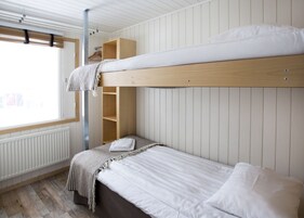 Dormitorio con literas, ventana, estanterías de madera y radiador.