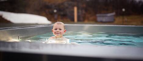 Un niño en un jacuzzi con un paisaje nevado al fondo.