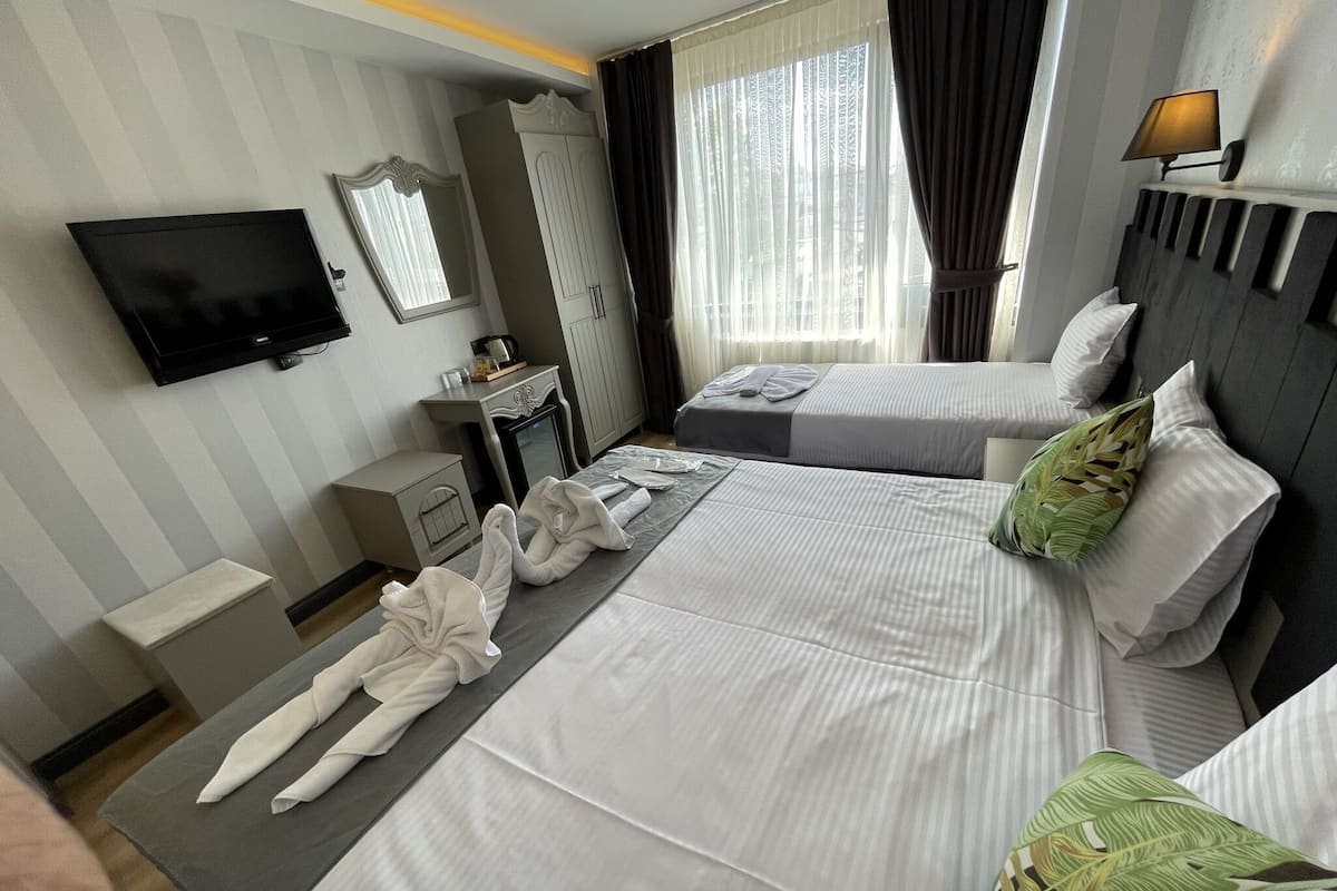A hotel room with two beds, a TV, a desk, and a wardrobe.