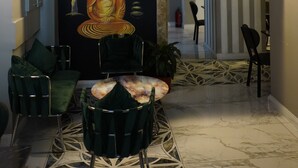 Un vestíbulo con una estatua de Buda, un anuncio de spa y una zona de estar con sillas y una mesa.