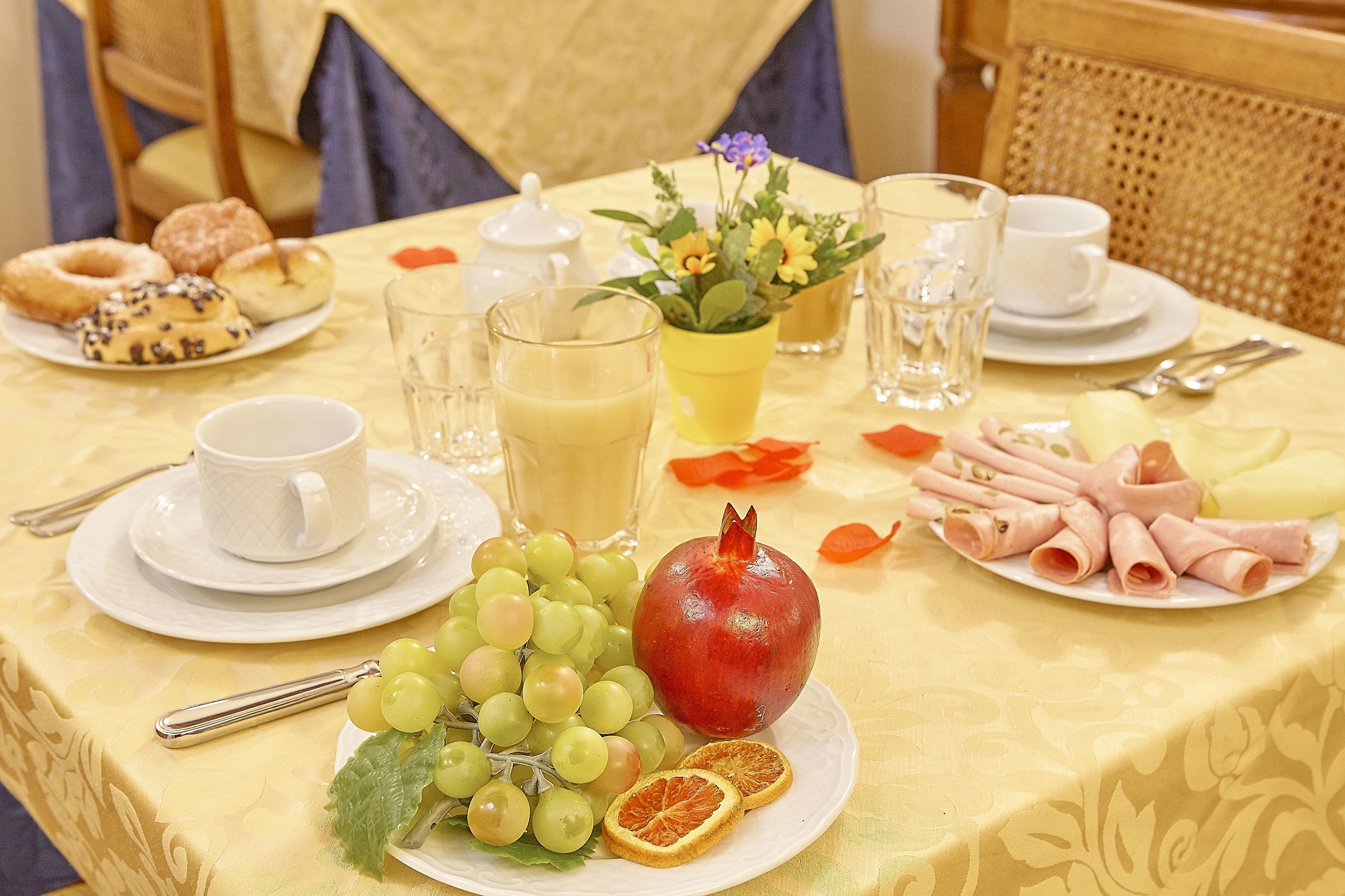 A breakfast table with a variety of food items including pastries, fruits, and beverages.