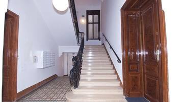 Un escalier avec une rampe en bois et un luminaire placé au-dessus.