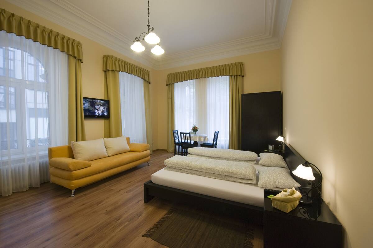 Une chambre d’hôtel comprenant un lit, un canapé, une télévision et une table à manger avec des chaises.