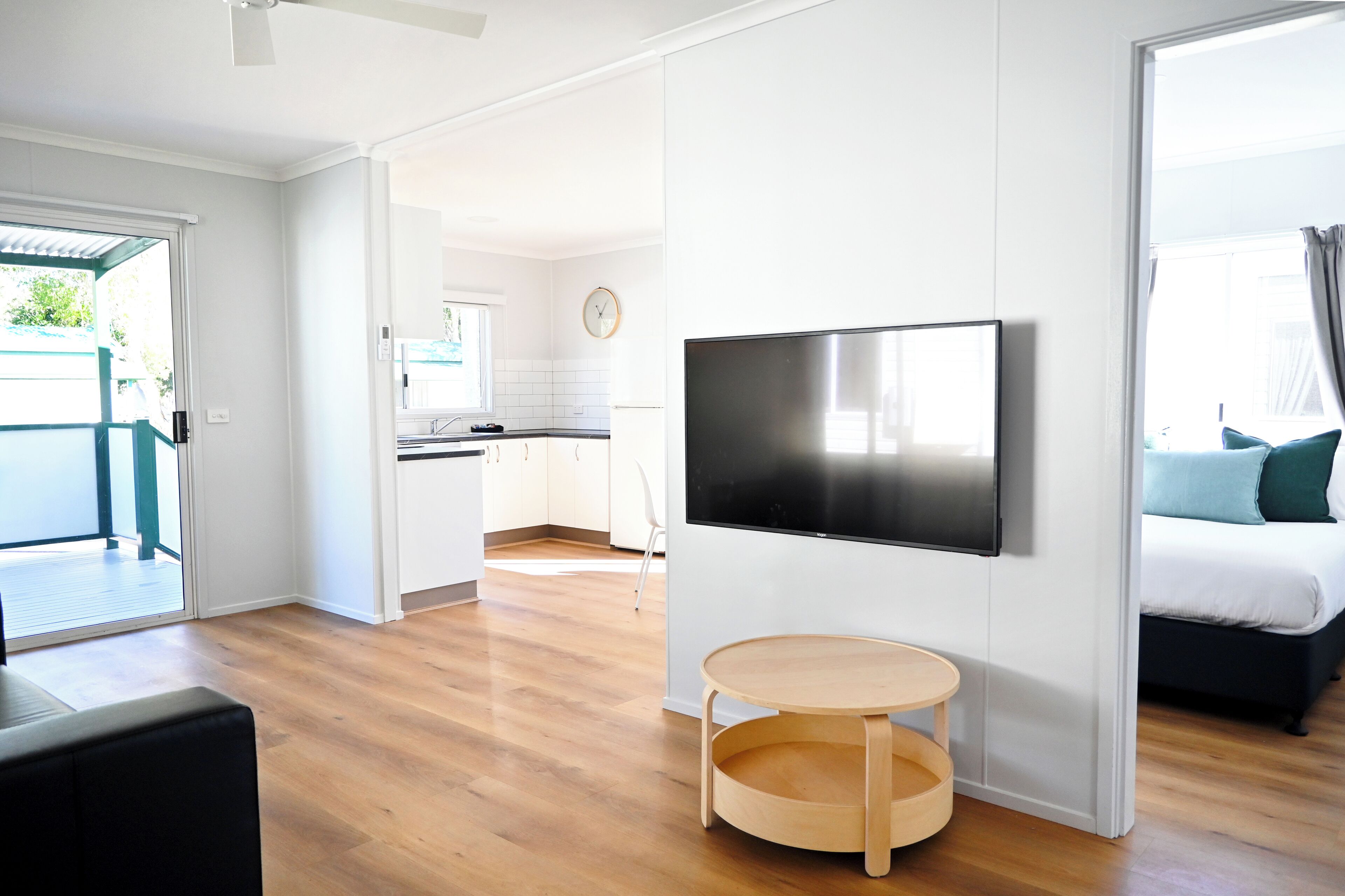A modern living room with a flat-screen TV, a round wooden table, and a sofa.