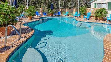 Ein Swimmingpool mit blauen Fliesen, umgeben von Liegestühlen und Topfpflanzen.