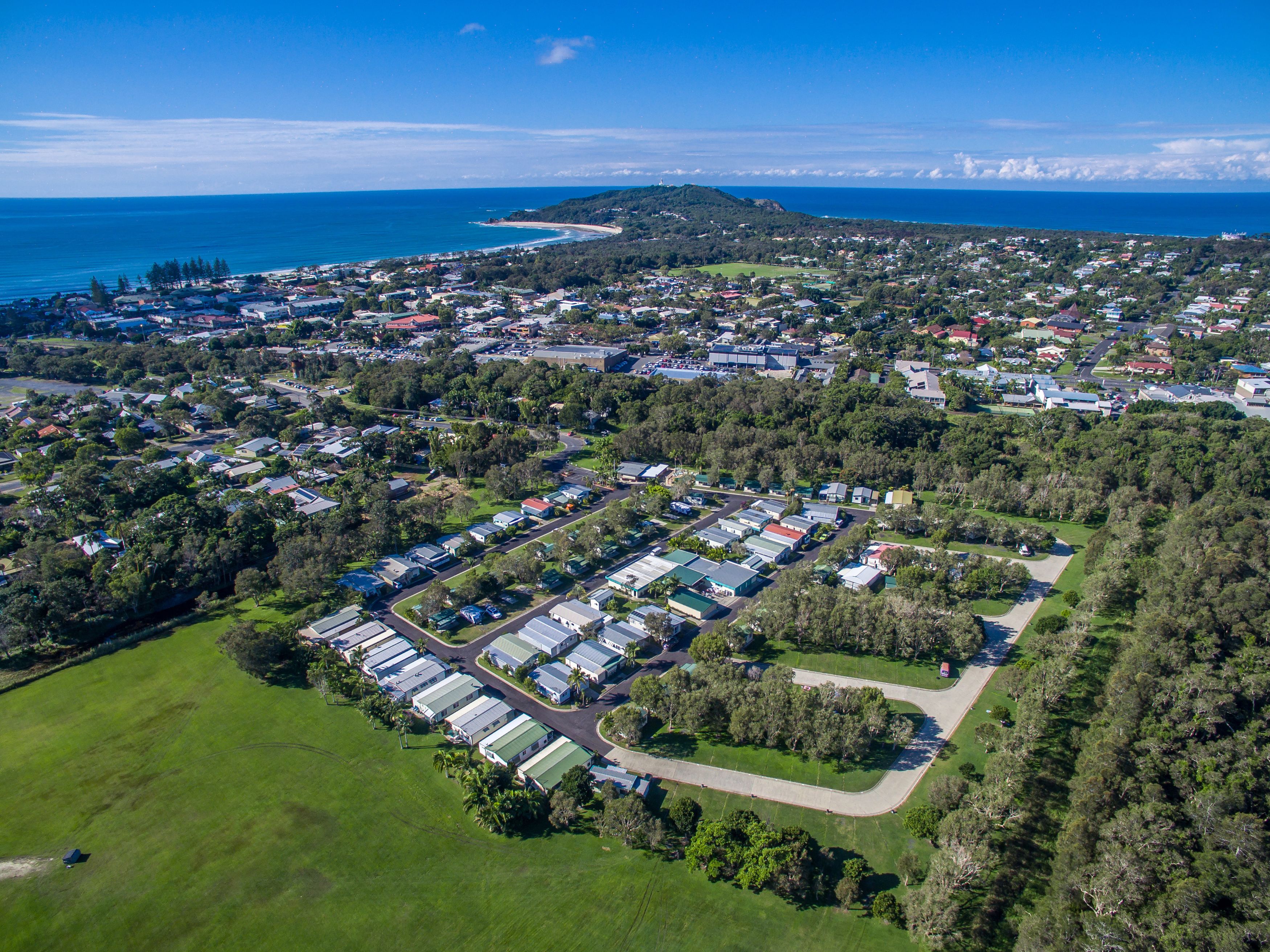 Vista aérea de una zona residencial con numerosas casas, un puerto deportivo y un paisaje montañoso al fondo.