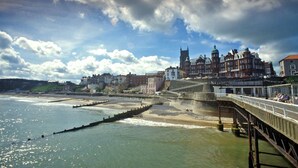 A coastal town with historic buildings, a pier, and a sea wall.