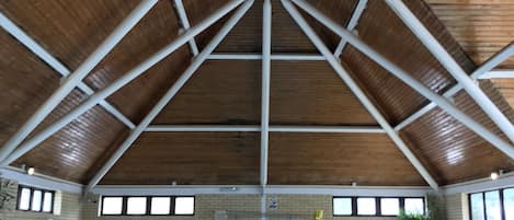An indoor swimming pool with a wooden ceiling and brick walls.