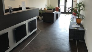 A reception area with a counter, seating, and potted plants. - The Links Country Park Hotel (Cromer)