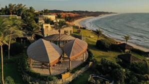 A coastal resort with thatched-roof structures, a sandy beach, and a view of the ocean. - Kilombo Villas & Spa (Tibau do Sul)