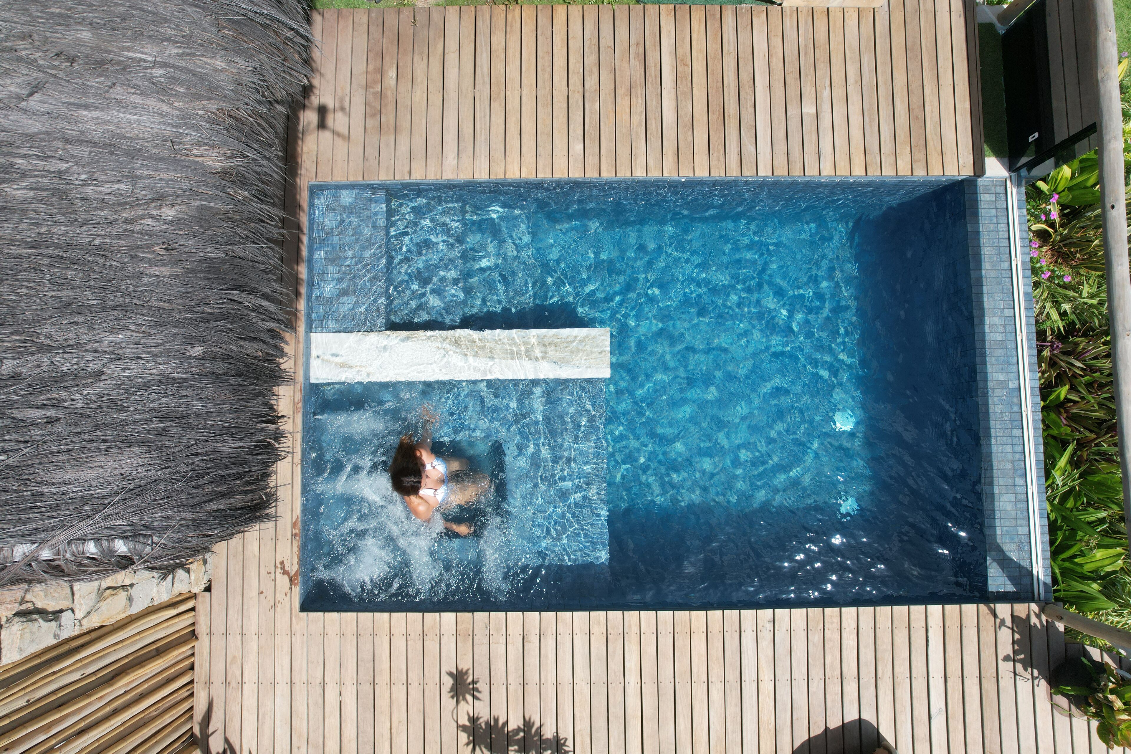 A rectangular swimming pool with clear blue water, surrounded by a wooden deck.