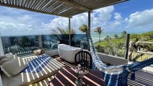 A balcony with a hammock, a sofa, and a small table with a vase of flowers. - Kilombo Villas & Spa (Tibau do Sul)
