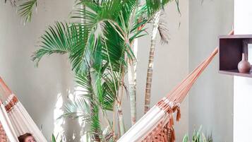 Relax in a hammock suspended between palm trees, surrounded by lush greenery and potted plants.