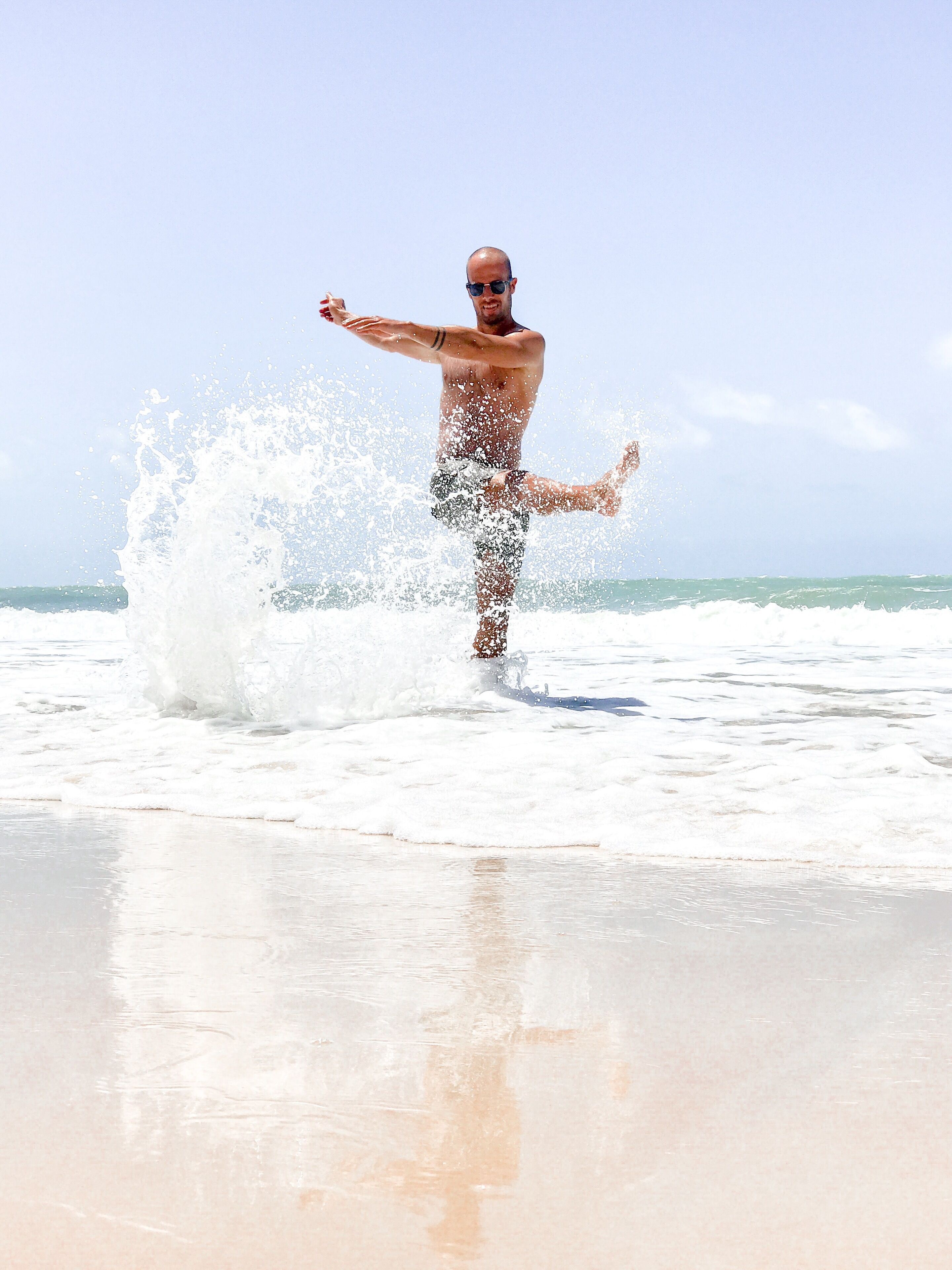 A man standing on a beach with waves crashing around him.