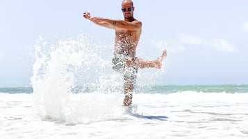 A man standing on a beach with waves crashing around him.