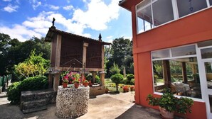 A courtyard with a traditional wooden structure, potted plants, and a modern building with large windows. - Casa Grande da Capellanía (Padron)