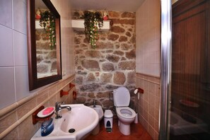 A bathroom with a stone wall, a sink, a toilet, and a shower. - Casa Grande da Capellanía (Padron)