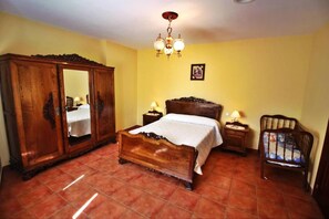 A bedroom with a wooden bed, a wardrobe, a nightstand, a chair, and a chandelier. - Casa Grande da Capellanía (Padron)