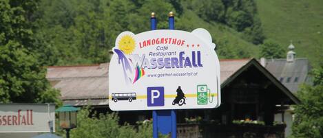 A sign for Landgasthof Café Restaurant Wasserfall with parking and electric vehicle charging symbols.