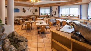 A restaurant with wooden furniture, stone walls, and a large antler decoration. - Hotel Wasserfall (Fusch an der Grossglocknerstrasse)