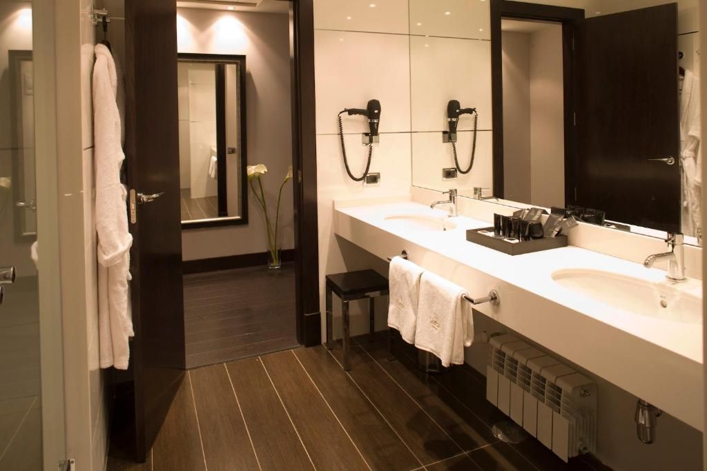 A modern bathroom with dual sinks, a large mirror, and a shower area.