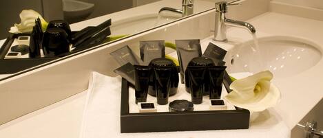 A hotel bathroom with a sink, mirror, and toiletries arranged on a tray.