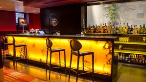 Un espace bar doté d’un comptoir en marbre, de tabourets de bar et d’une variété de bouteilles d’alcool.