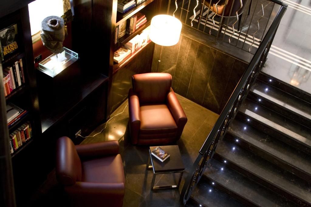 Un interior moderno con un sillón de cuero, una mesita con un libro y una escalera con barandilla.
