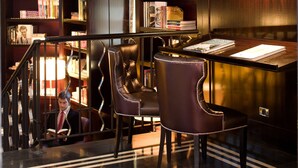Une bibliothèque à plusieurs niveaux, avec des étagères, des fauteuils en cuir et un escalier.