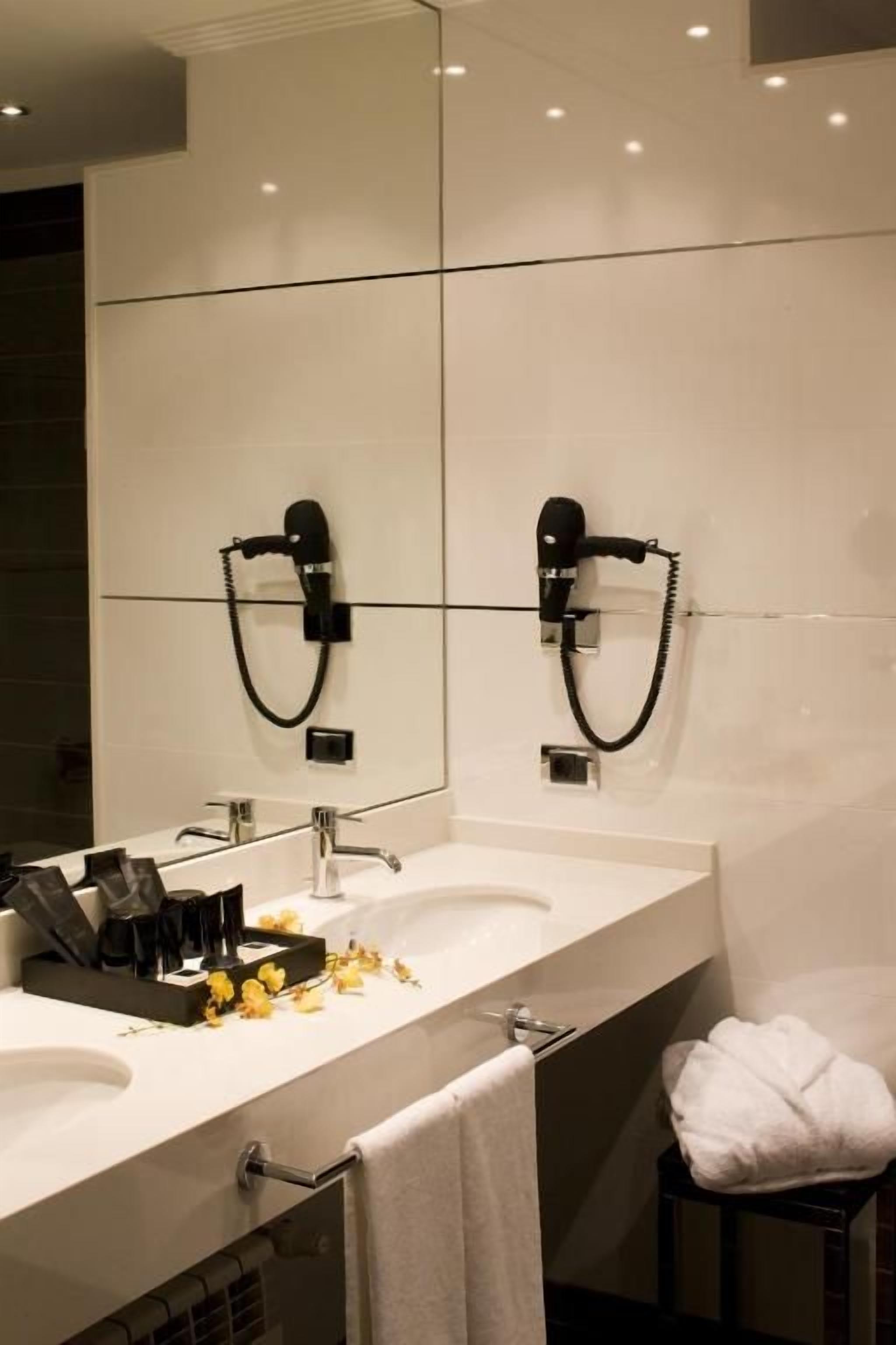 Une salle de bain moderne avec deux lavabos, un miroir et un porte-serviettes.