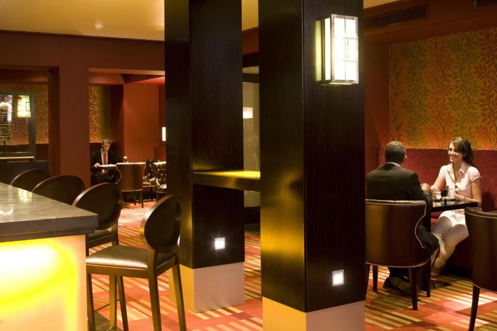A restaurant with a bar area, seating arrangements, and a patterned wall.