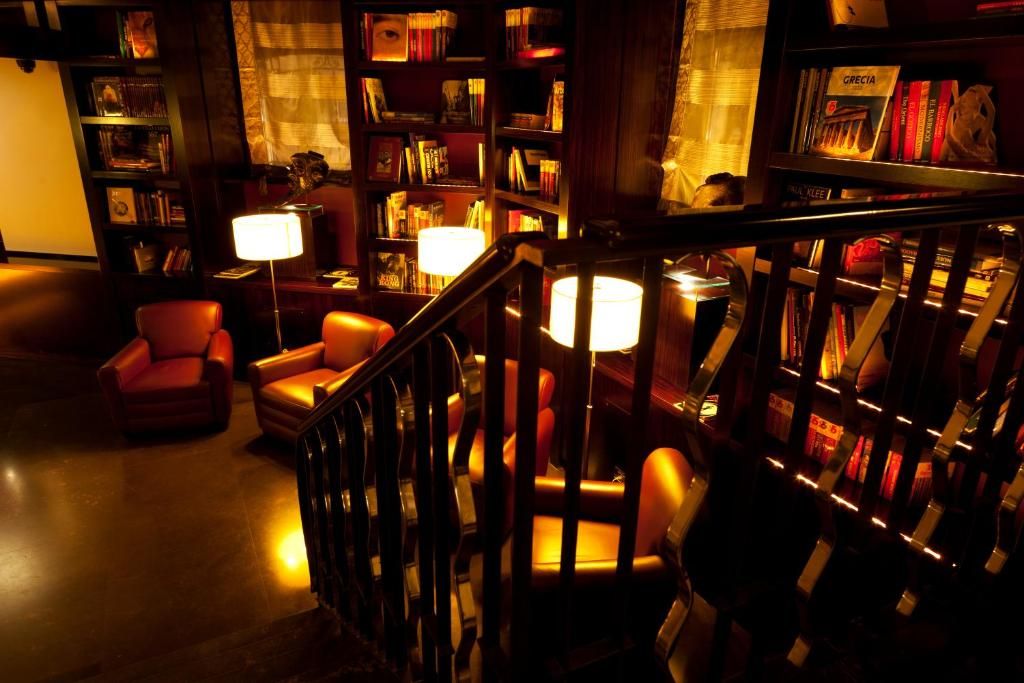 A cozy reading area with leather chairs, a wooden staircase, and a bookshelf filled with books.