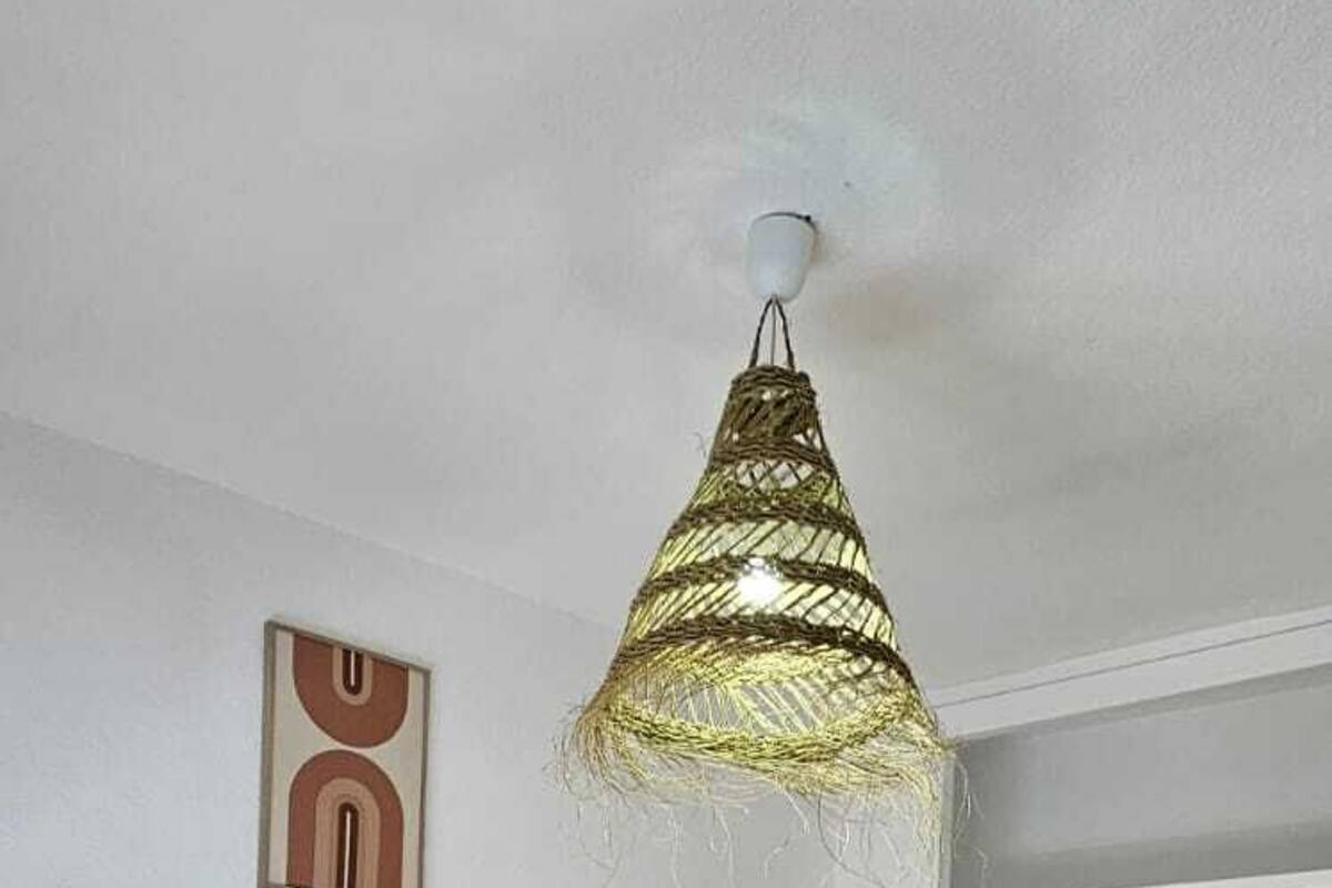 Un dormitorio con dos camas, una lámpara colgante, una repisa con objetos decorativos y un espejo.