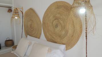 A room with a bed, two large woven wall hangings, a hanging light fixture, and a woven basket on a shelf.