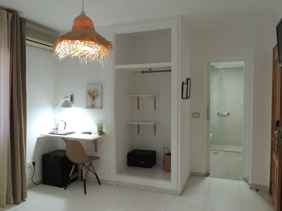 Un dormitorio moderno con escritorio, silla y lámpara colgante.