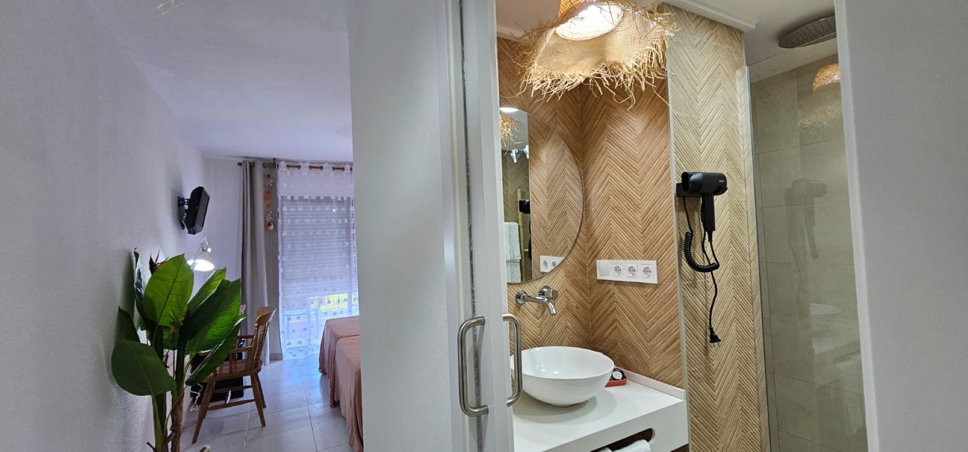 A bathroom with a white sink, a mirror, and a hairdryer on the wall.