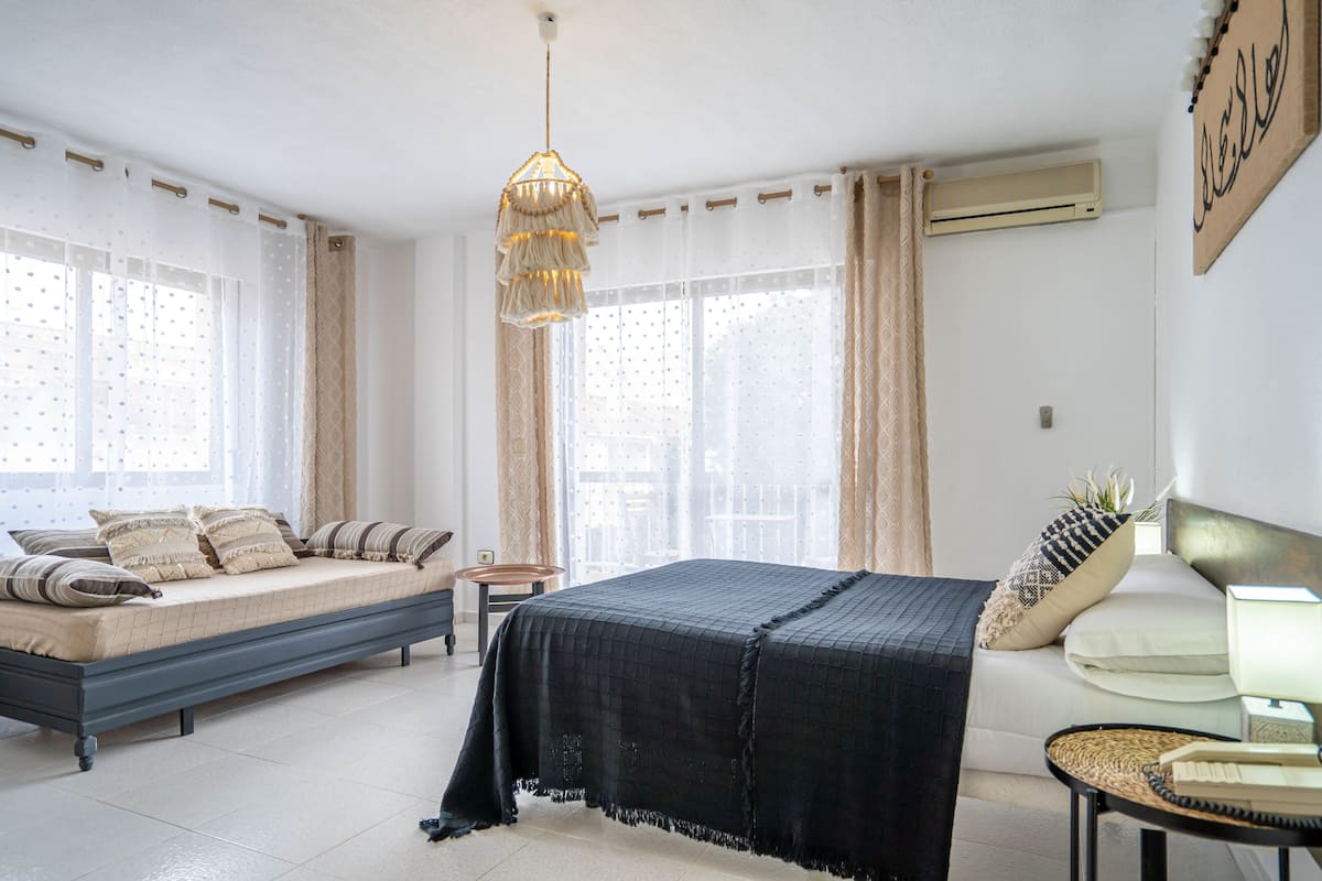 Un dormitorio con cama, mesita de noche y lámpara colgante.