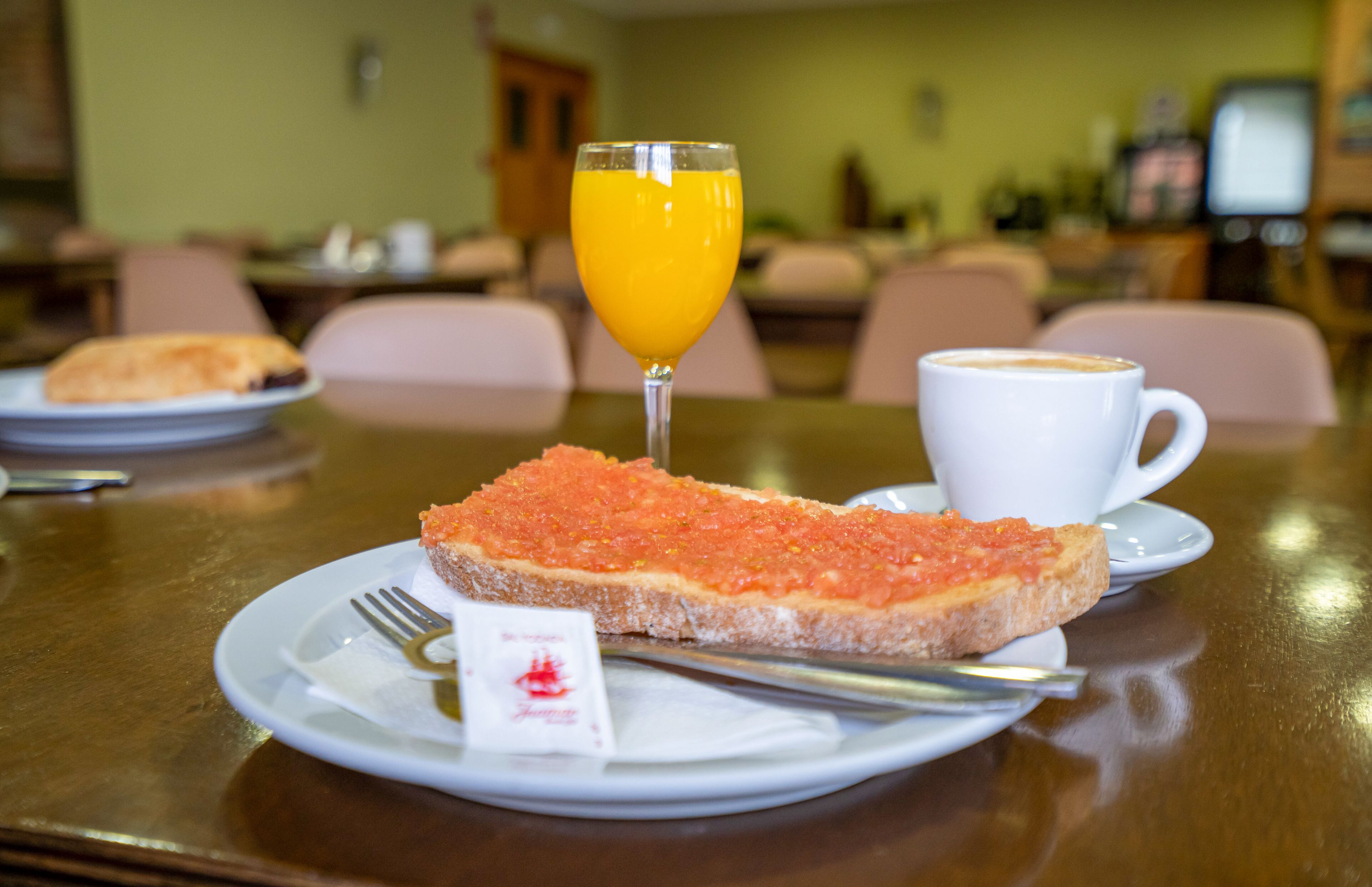 Une table en bois dressée pour le petit-déjeuner, avec une assiette de toasts recouverts de caviar rouge, un verre de jus d’orange et une tasse de café.