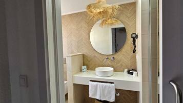 Un baño moderno con un espejo redondo, un lavabo blanco y una toalla colgada en la pared.