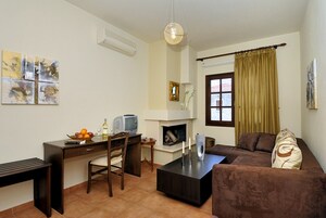 Una sala de estar con un sofá marrón, una mesa de centro, un televisor sobre un mueble de madera, una chimenea y obras de arte en la pared.